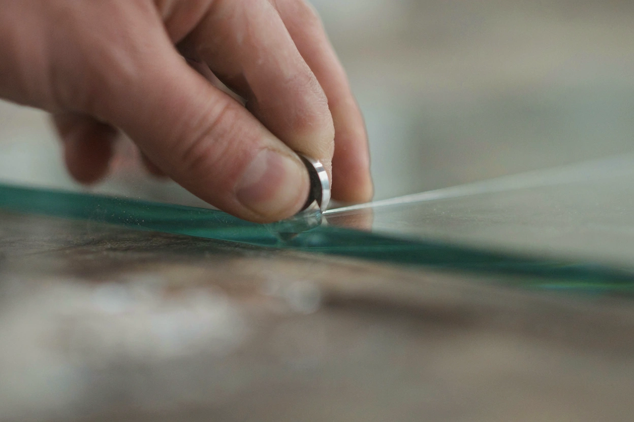 Découpe d'une vitre à la molette dans l'atelier